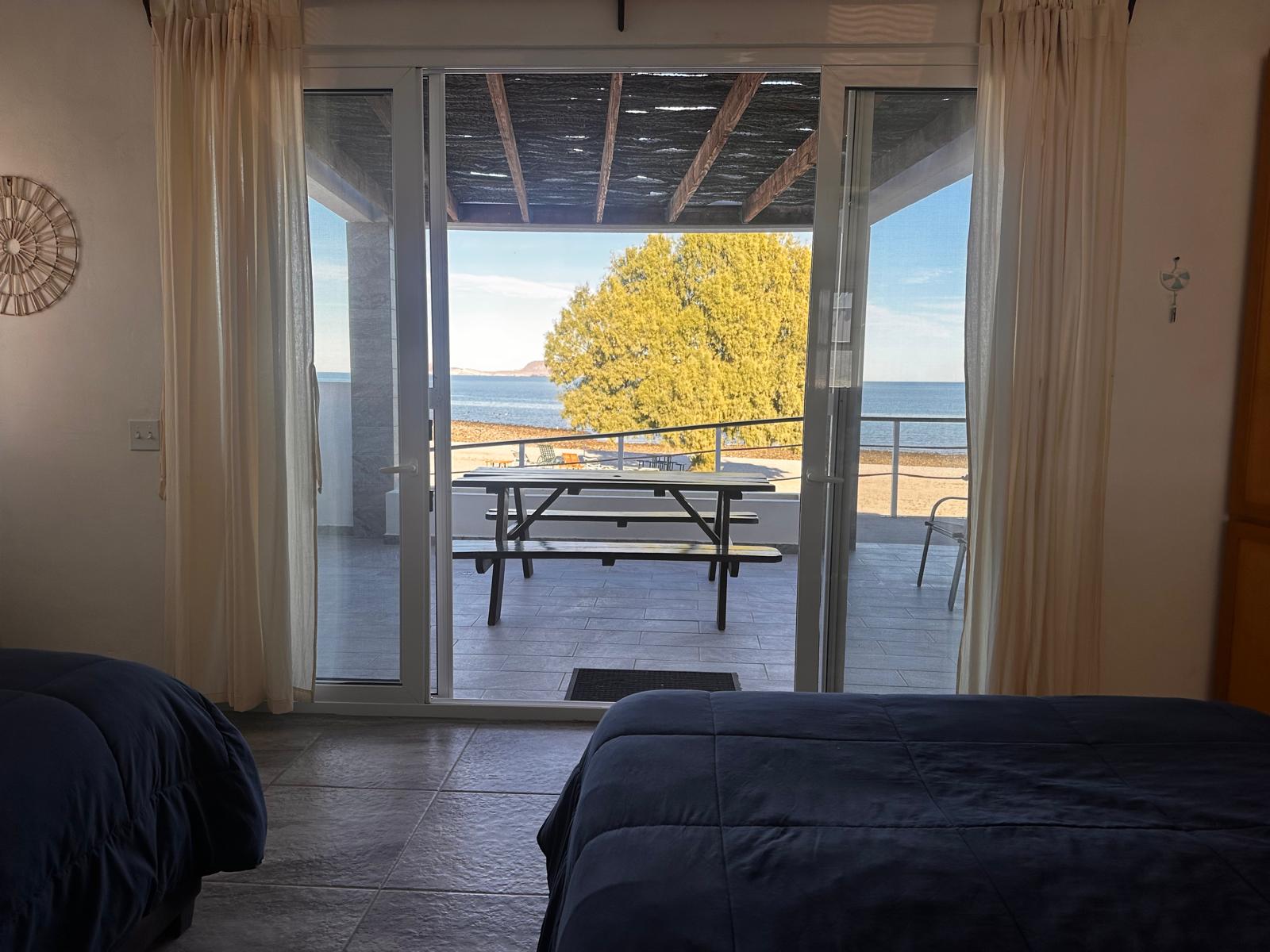 Puertas abiertas de la habitación hacia la terraza y el mar al amanecer